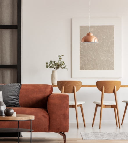 Séjour lumineux d'une maison neuve sur mesure avec canapé terracotta et chaises en bois