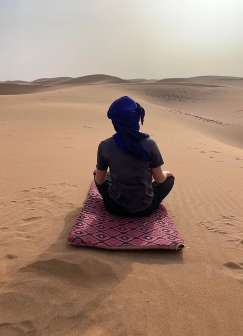 Femme assise de dos en méditation dans le désert lors d'une retraite spirituelle