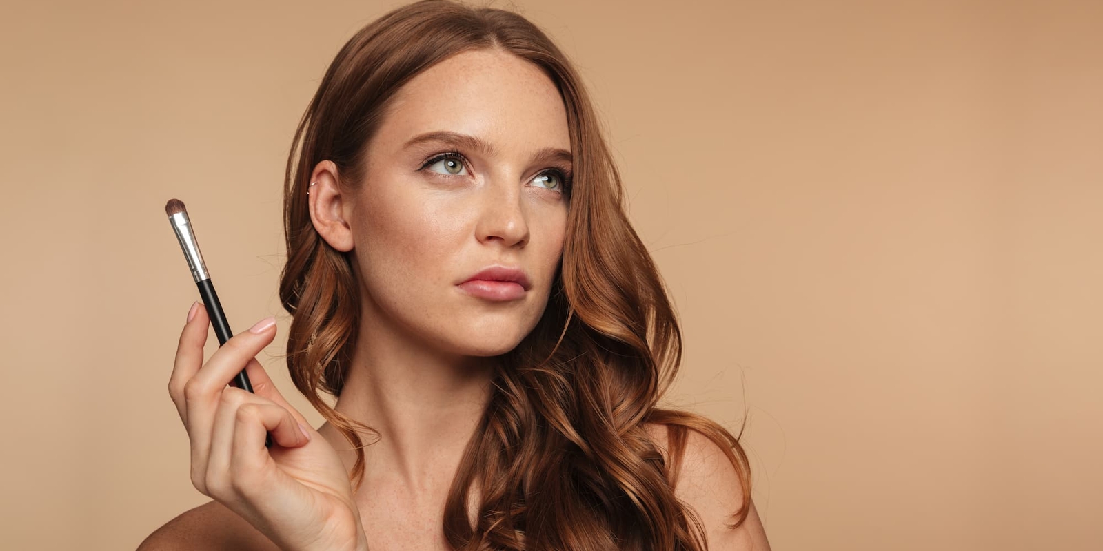 Femme se maquillant avec un pinceau, prenez rendez-vous a l'institut Terre de Beaute