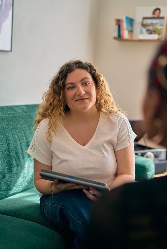 Clothilde Bernard de CloAssist, assise sur un canapé avec sa tablette, en rendez-vous