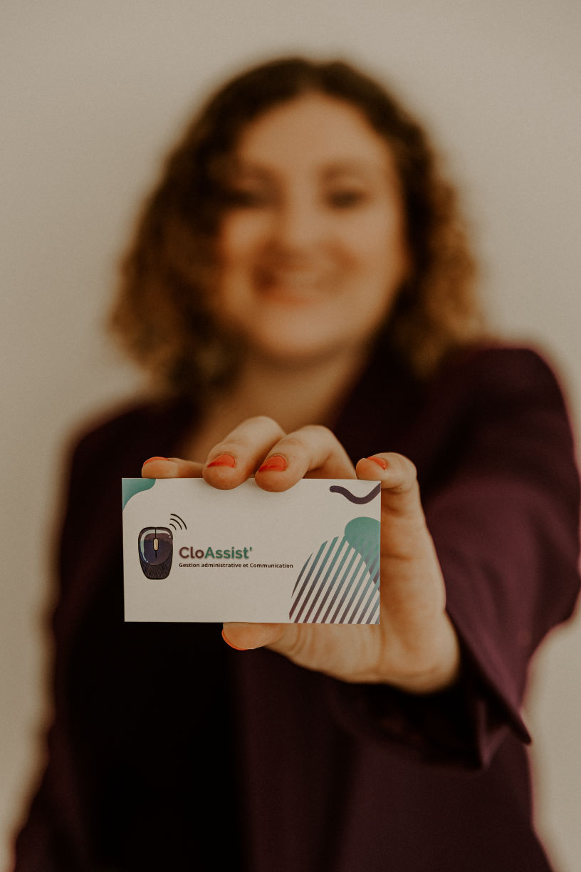 Clothilde tend une carte de visite CloAssist' vers l'objectif