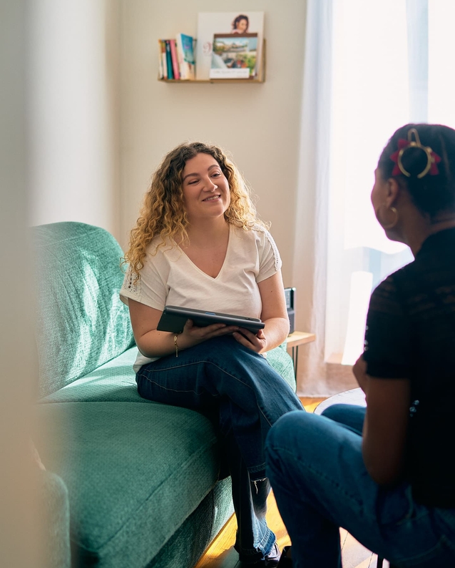Clothilde échangeant avec une personne formée, assise sur un canapé avec sa tablette