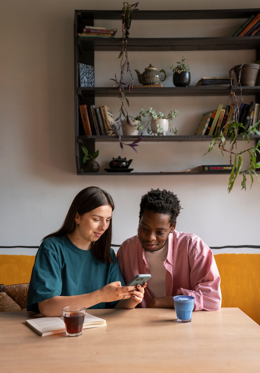 Deux personnes penchées sur un téléphone, en pleine réflexion sur leur stratégie marketing