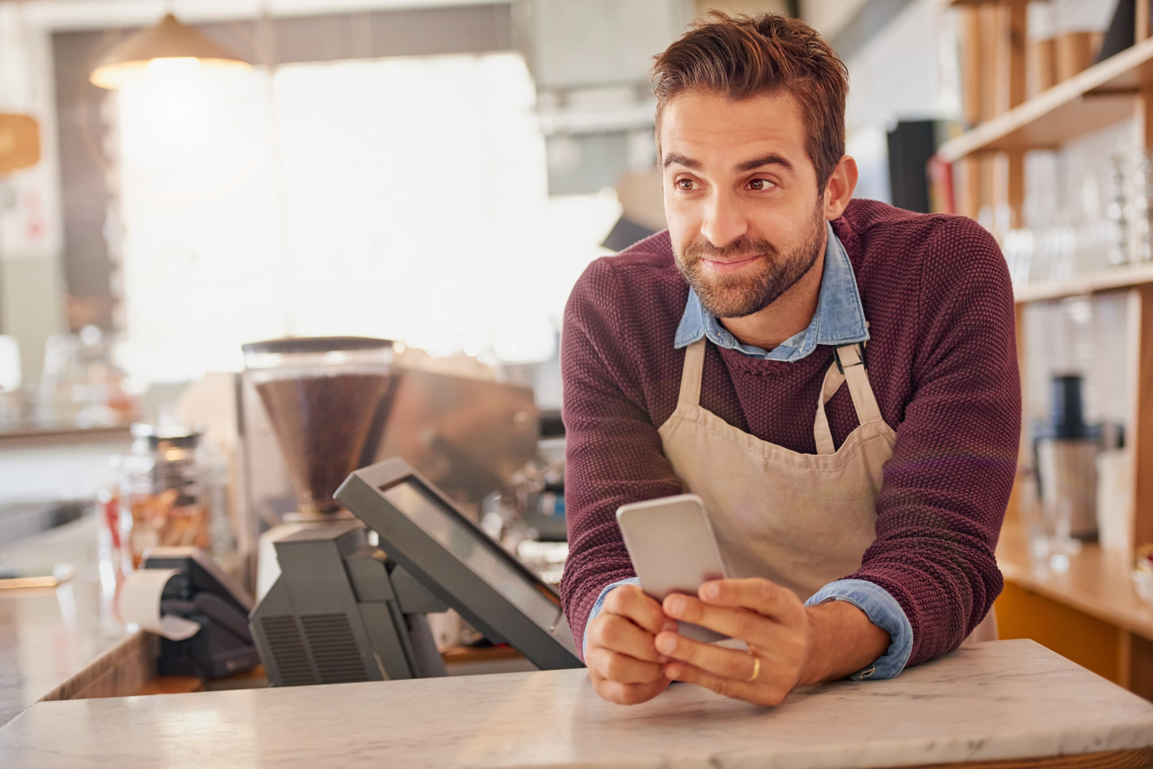 barista-sur-son-telephone-souriant