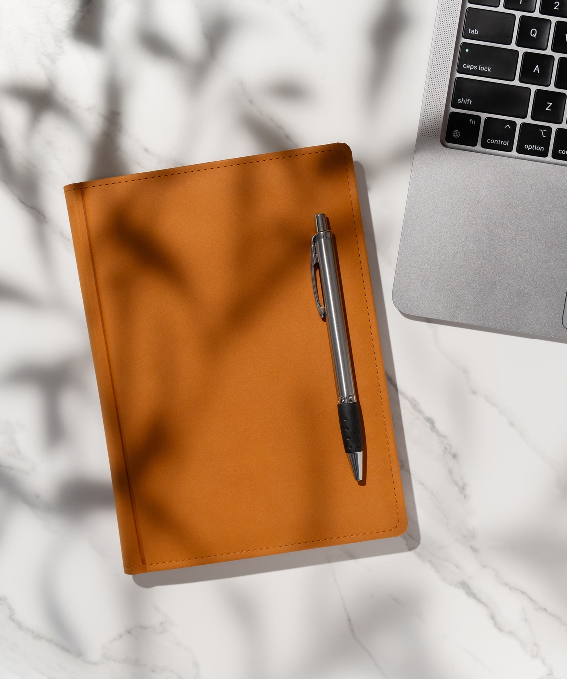 Carnet en cuir à côté d’un ordinateur portable