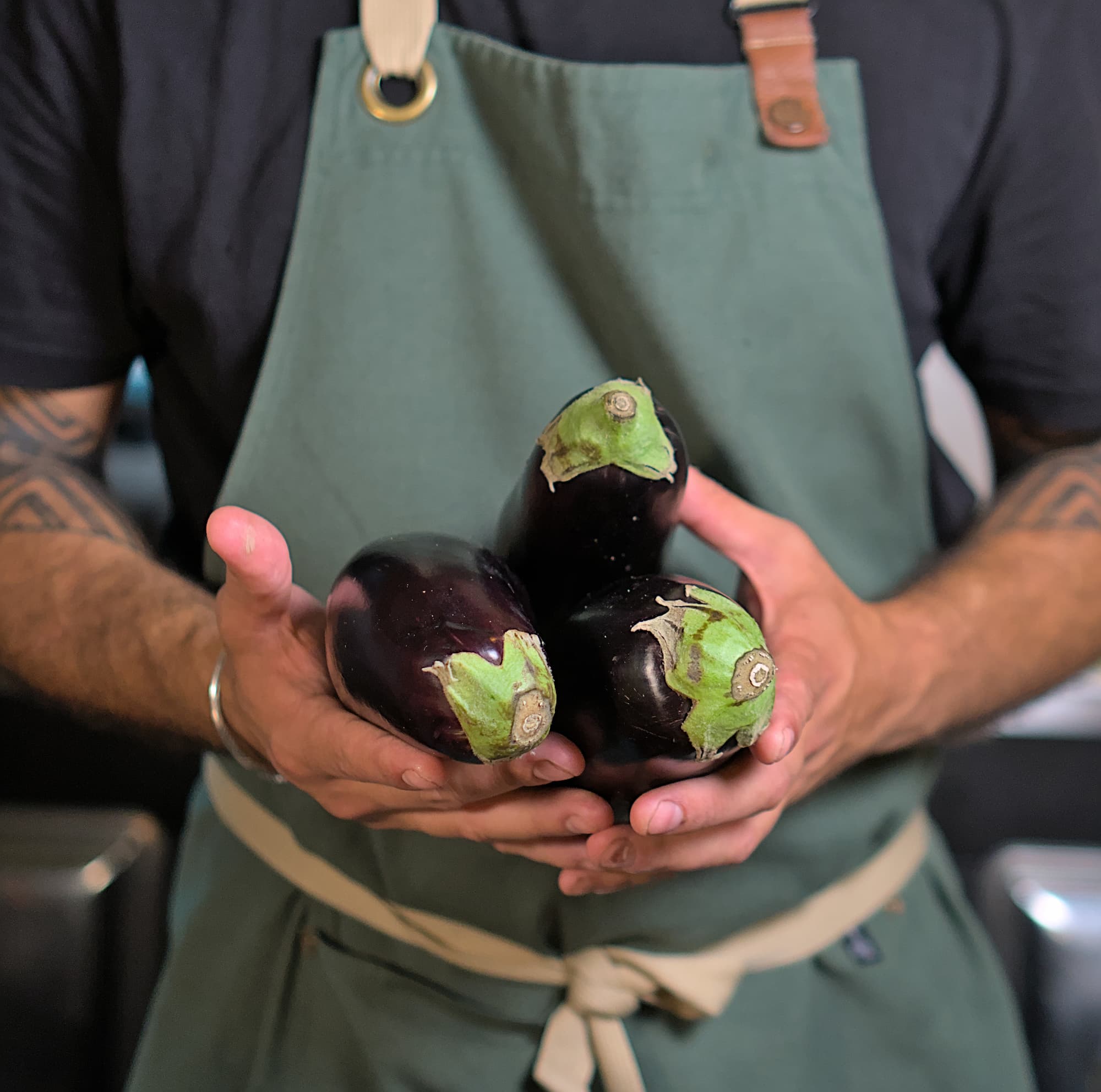 gros-plan-cuisinier-tenant-des-aubergines-dans-ses-mains