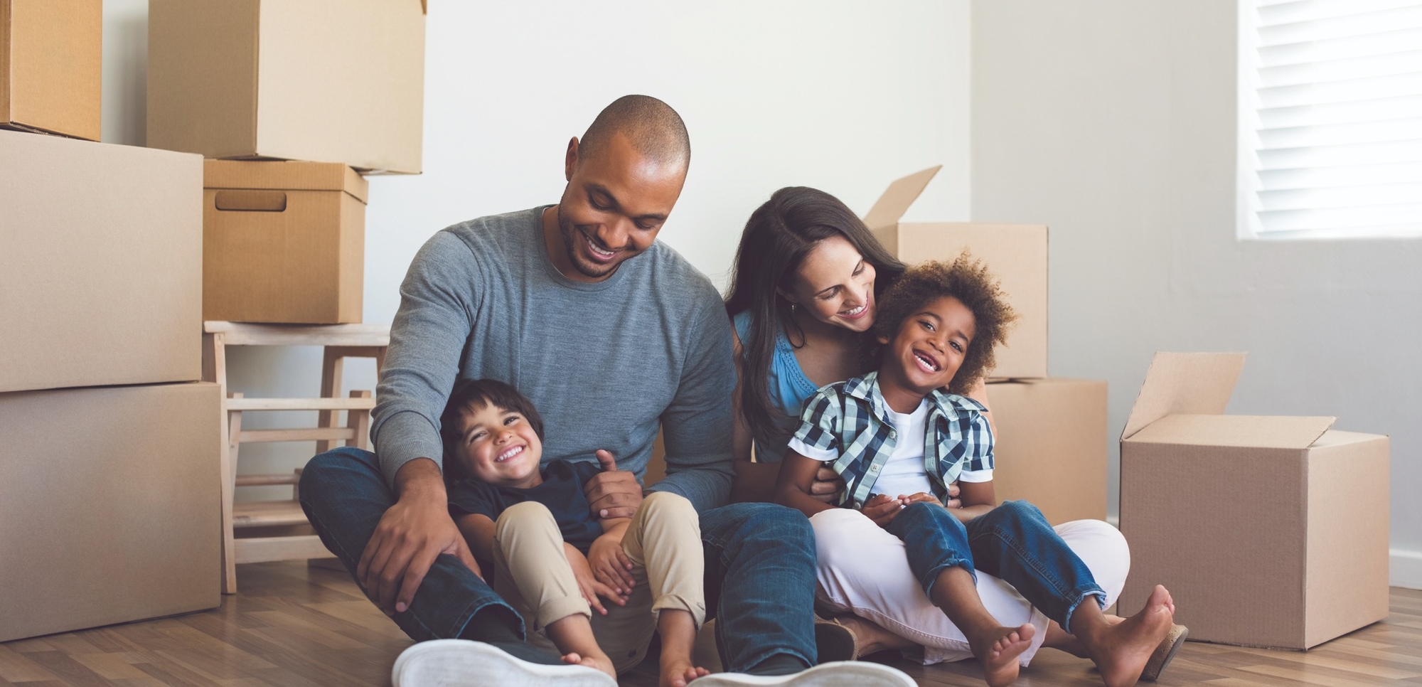 Famille souriante assise au milieu des cartons de déménagement