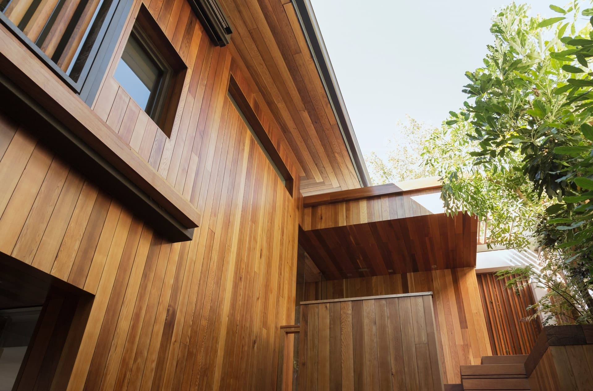 Gros plan en contre-plongée sur le bardage et la sous-face bois d'une maison moderne