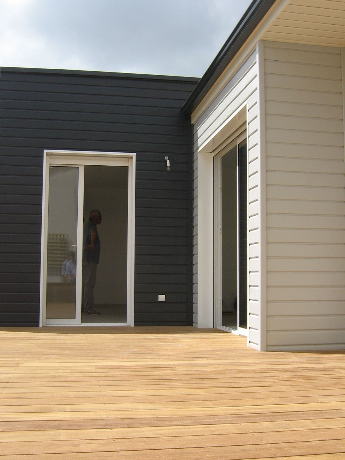 Gros plan sur la terrasse bois et les façades d'une maison traditionnelle en ossature bois