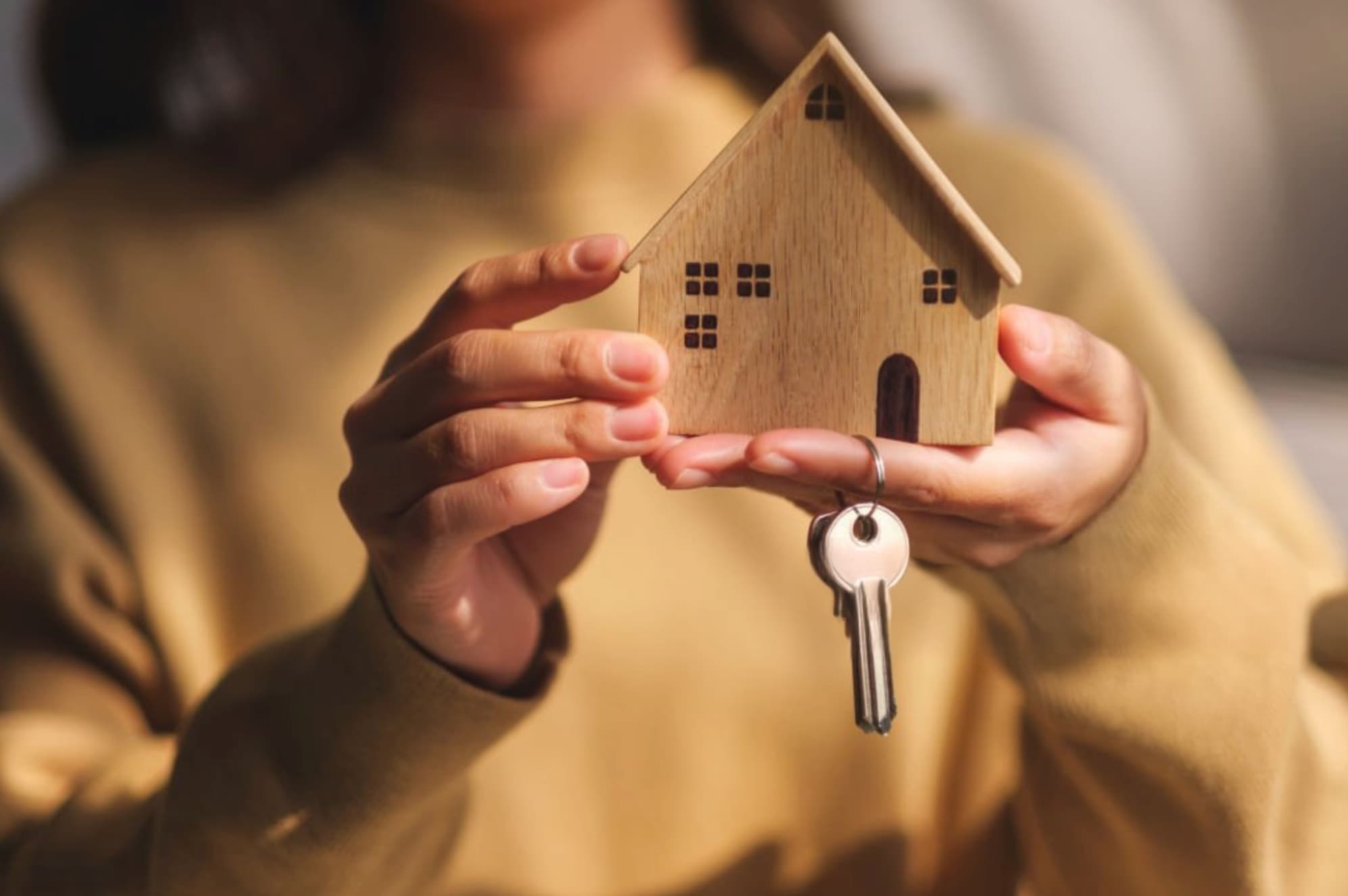 Remise des clés d'une maison avec un porte-clés en forme de maison en bois