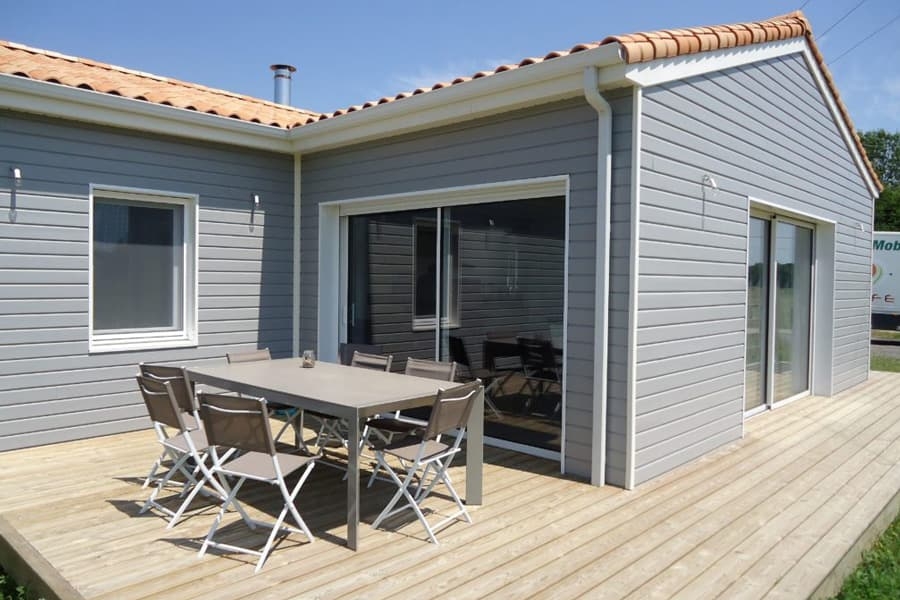 Maison en ossature bois avec un bardage bois peint et une terrasse