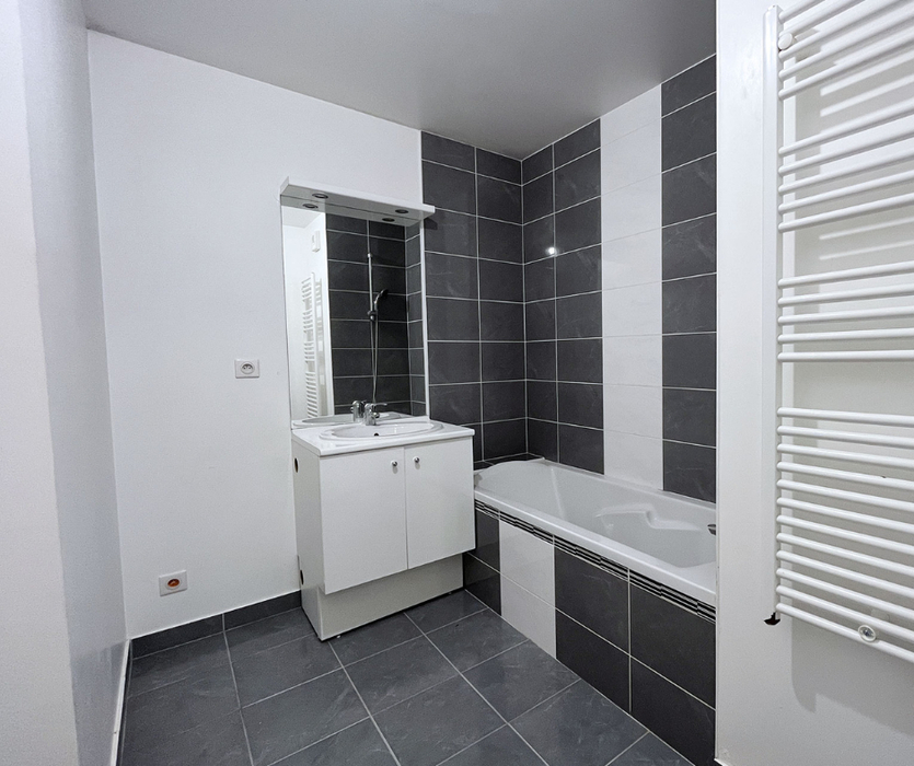 Salle de bains moderne grise et blanche, froide avant home staging à Nantes avec baignoire, carrelage gris et blanc, meuble vasque blanc