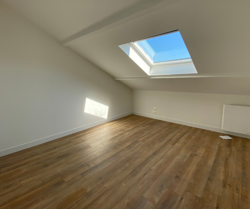 Chambre en sous pente avec fenêtre de toit murs blancs parquet vide pour la vente