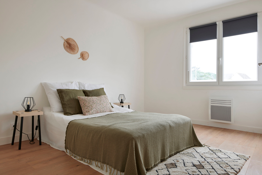 Chambre parentale aménagée avec un lit, tables de chevet, coussins, plais, tapis après home staging à Pornichet