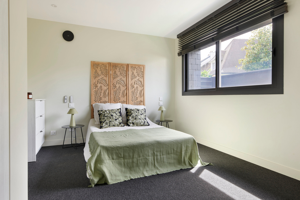 Chambre avec tete de lit bois, textiles coussins verts et noir apres home staging a nantes