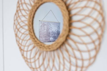 Reflet d'une déco murale dans un miroir rond en osier