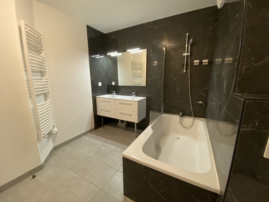 Salle de bain aux murs en marbre noir dans appartement neuf avant home staging à Nantes quartier Chalatres