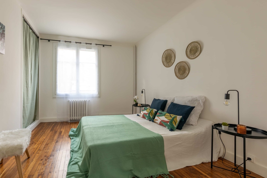 chambre parentale meublée pour la vente grâce au home staging à Nantes avec lit chevets pouf rideaux plaid coussins lampes