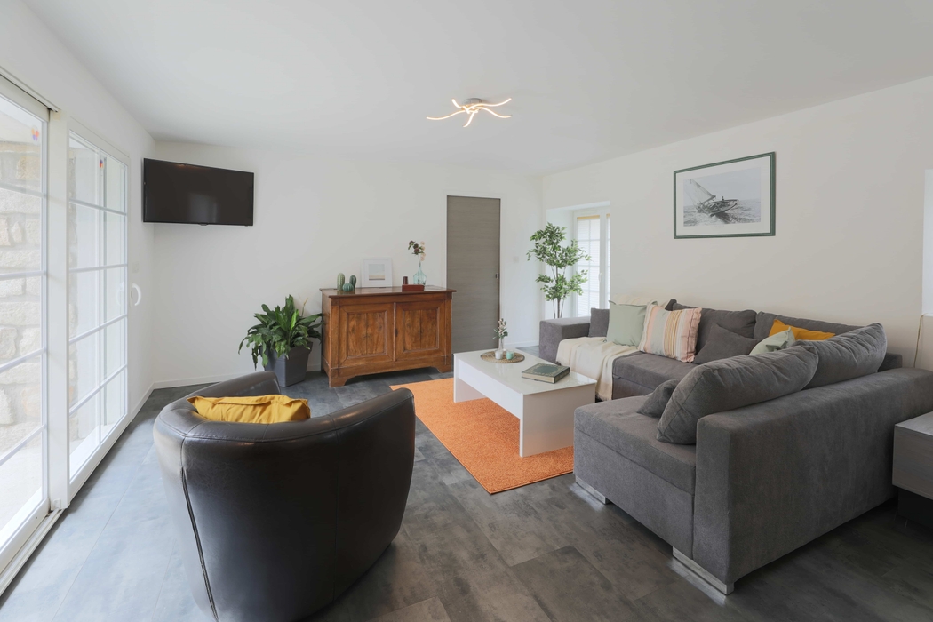 salon rangé épuré avec meuble en bois canapé gris tapis rouille table basse blanche fauteuil cuir après home staging en bretagne