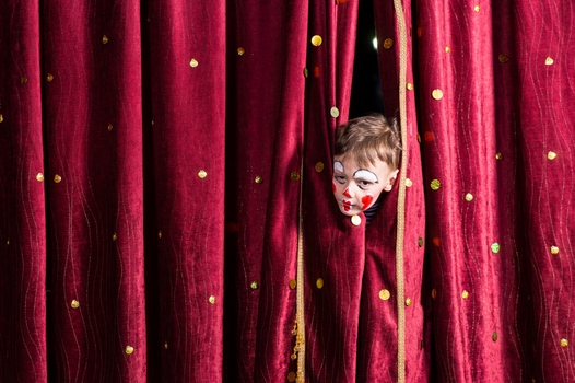 Enfant qui se cache derrière un rideau de théâtre