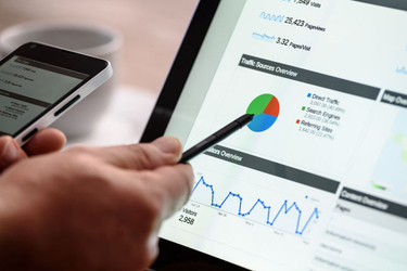 Main qui pointe avec un stylet des statistiques de trafic web sur une tablette
