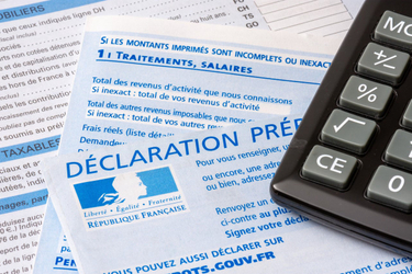 Formulaire de déclaration de revenus pré-remplie posé à côté d'une calculatrice