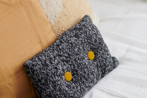 detail décoration de home staging avec trois coussins de couleur assorties gris jaune moutarde beige
