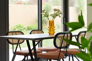 Table de salle a manger avec chaises vintage terracotta près de grandes baies vitrées