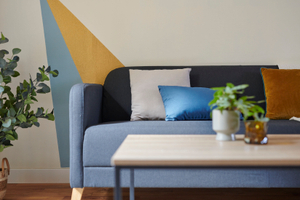 Canape avec coussins bleu beige mur avec peinture jaune doré table basse plante